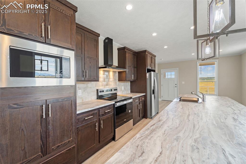 Image 16 of 44: Kitchen featuring stainless steel appliances, wall chimney exhaust hood, li