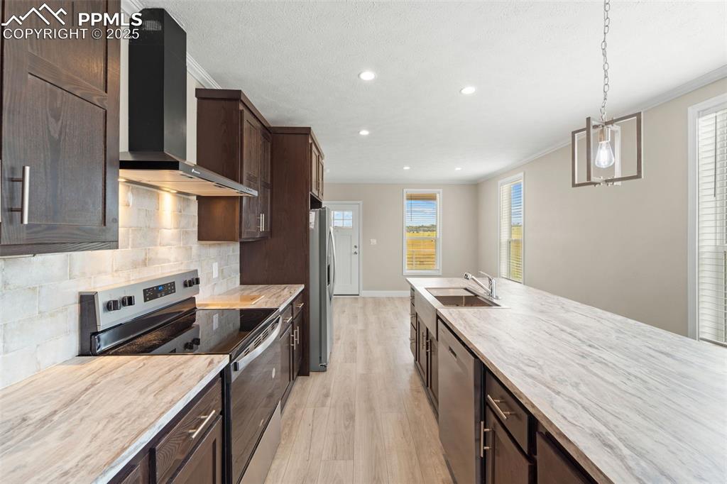 Image 17 of 44: Kitchen with stainless steel appliances, wall chimney range hood, light woo