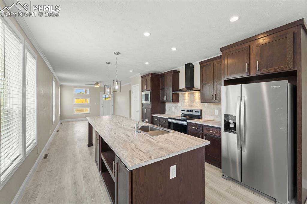 Image 19 of 44: Kitchen with stainless steel appliances, wall chimney exhaust hood, dark br