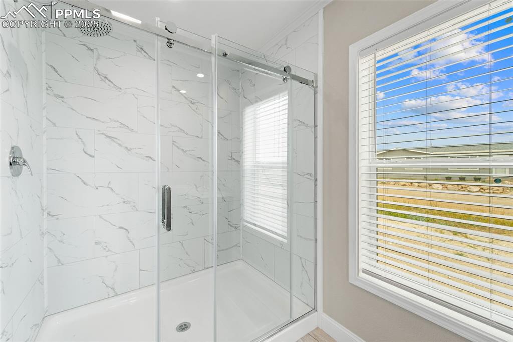 Image 25 of 44: Full bath featuring a marble finish shower and baseboards