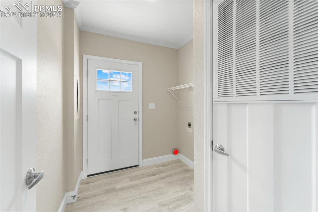 Image 29 of 44: Laundry area with ornamental molding, a heating unit, light wood-style floo