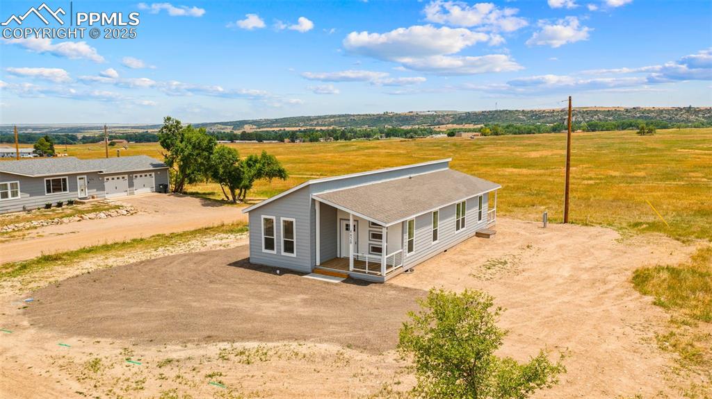 Image 35 of 44: Country-style home featuring dirt driveway, a porch, an attached garage, a
