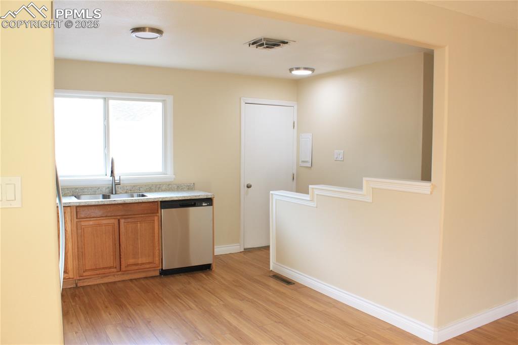Image 10 of 42: Kitchen with stainless steel dishwasher, a sink, brown cabinets, and light