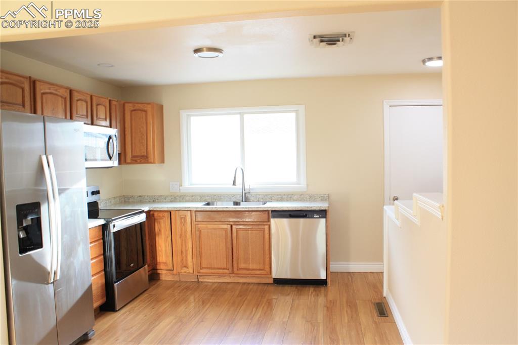 Image 6 of 42: Kitchen with appliances with stainless steel finishes, a sink, light counte