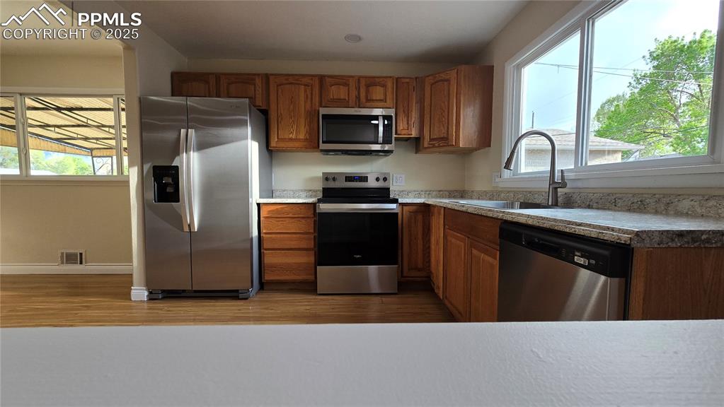 Image 8 of 42: Kitchen with stainless steel appliances, a sink, brown cabinets, and health
