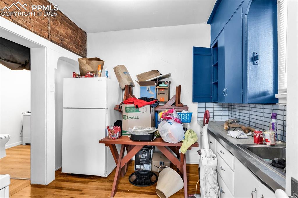 Image 23 of 50: Lower level, Unit A - Kitchen with backsplash and trendy blue cupboards