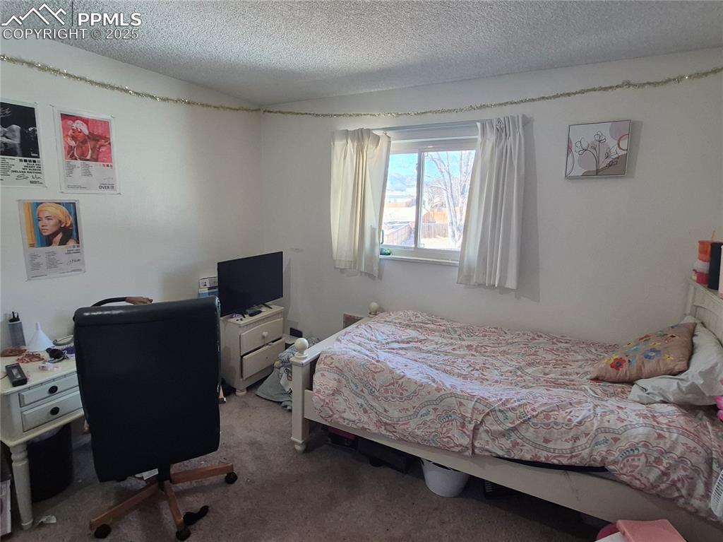 Image 5 of 7: Carpeted bedroom featuring a textured ceiling and an office area
