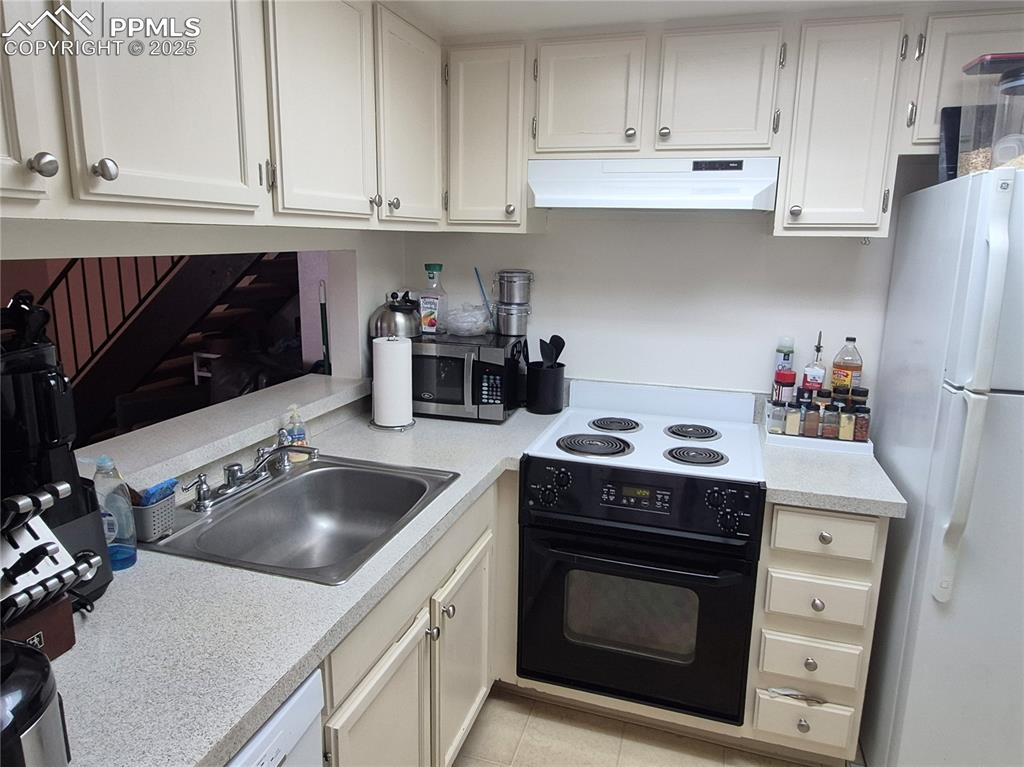 Image 6 of 7: Kitchen with black range, freestanding refrigerator, light countertops, and