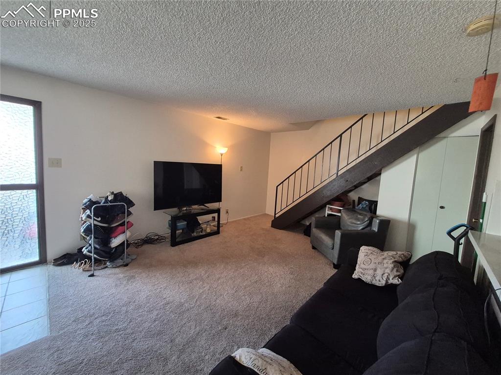 Image 7 of 7: Living room with carpet, a textured ceiling, and stairs