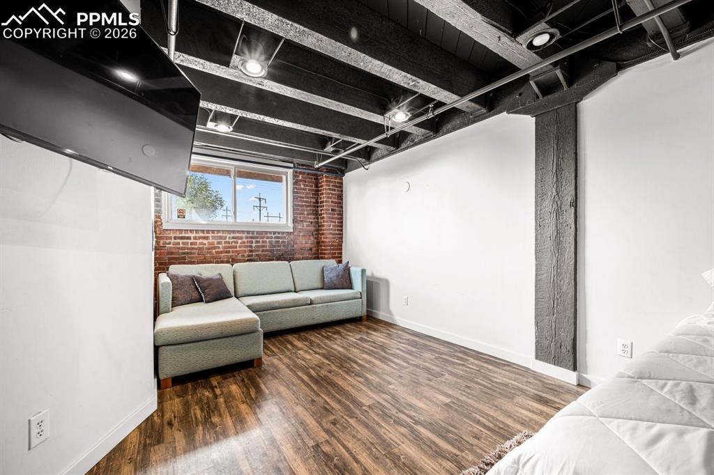 Image 27 of 32: Living room with brick wall and wood finished floors
