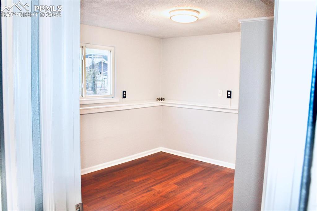 Image 10 of 15: Empty room featuring dark wood-style flooring and a textured ceiling