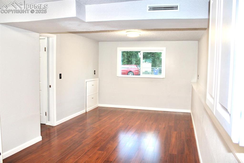 Image 12 of 15: Spare room featuring wood finished floors and a textured ceiling