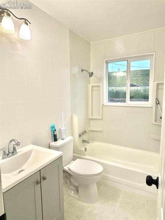 Image 13 of 15: Full bathroom with vanity, shower / bath combination, tile walls, and tile 