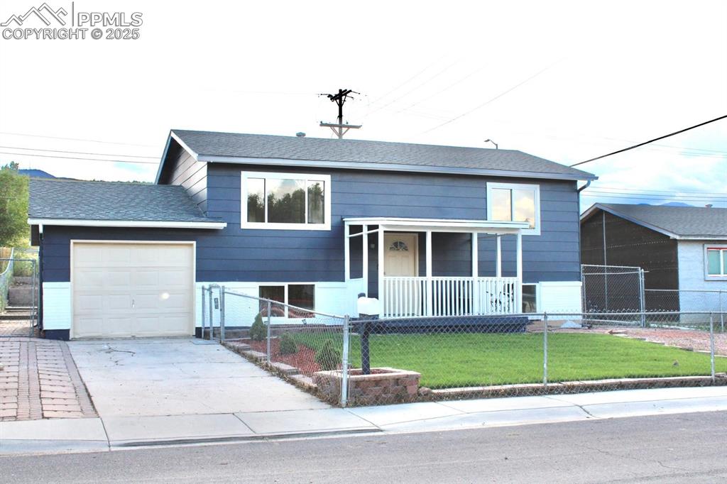 Image 2 of 15: View of front of home featuring covered porch, a fenced front yard, an atta