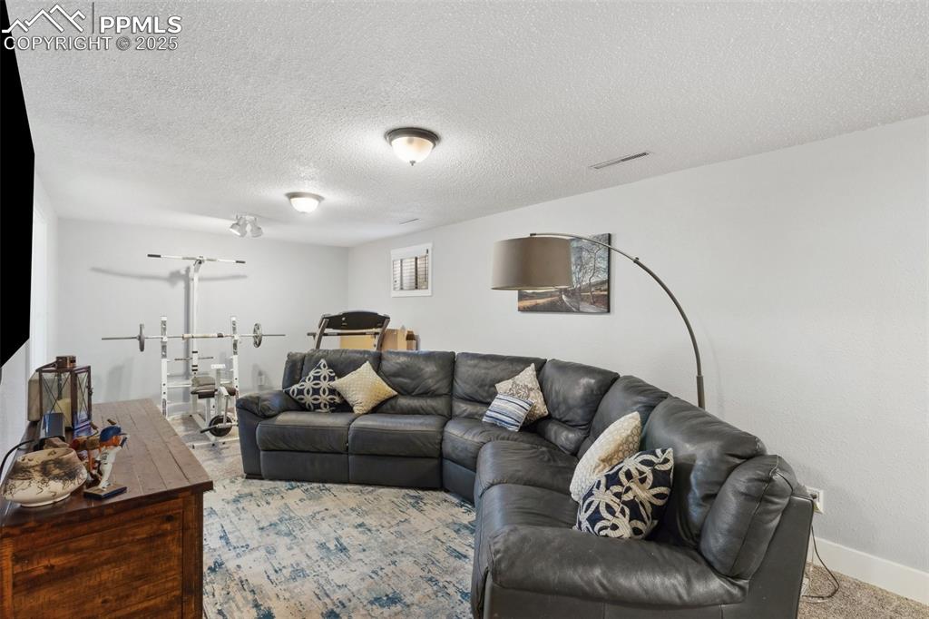Image 12 of 17: Living area featuring a textured ceiling and baseboards