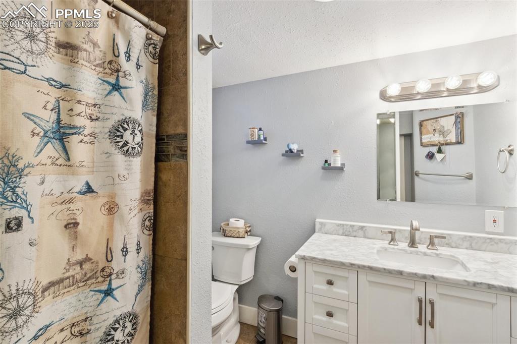 Image 14 of 17: Bathroom featuring a textured wall, a textured ceiling, vanity, and curtain