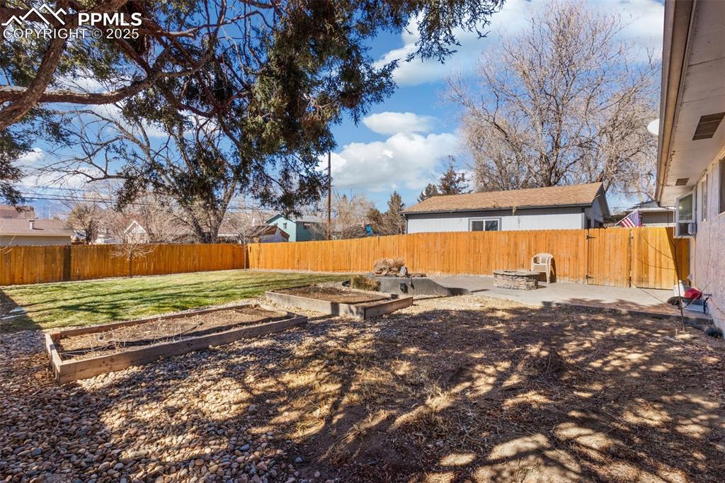 Image 16 of 17: Fenced backyard featuring a garden and a patio area
