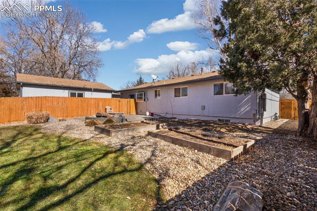 Image 17 of 17: Rear view of house featuring a vegetable garden and a patio area