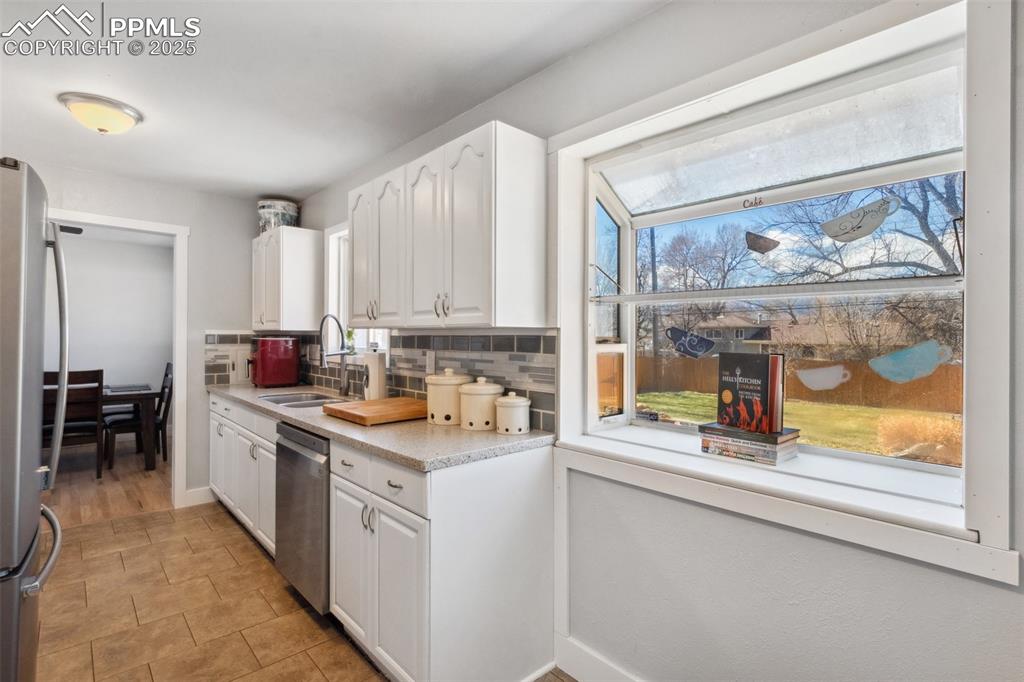 Image 6 of 17: Kitchen with light countertops, white cabinets, appliances with stainless s