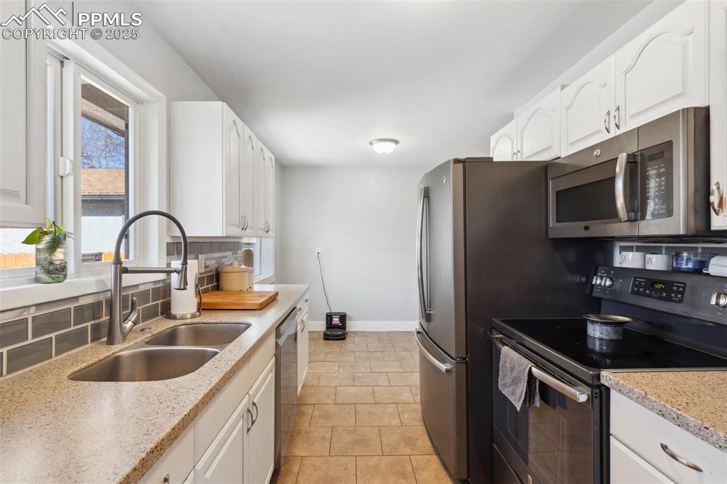 Image 7 of 17: Kitchen with appliances with stainless steel finishes, backsplash, white ca