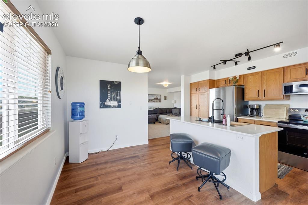 Image 10 of 40: Wood-finish flooring throughout, kitchen with light wood cabinetry, white c