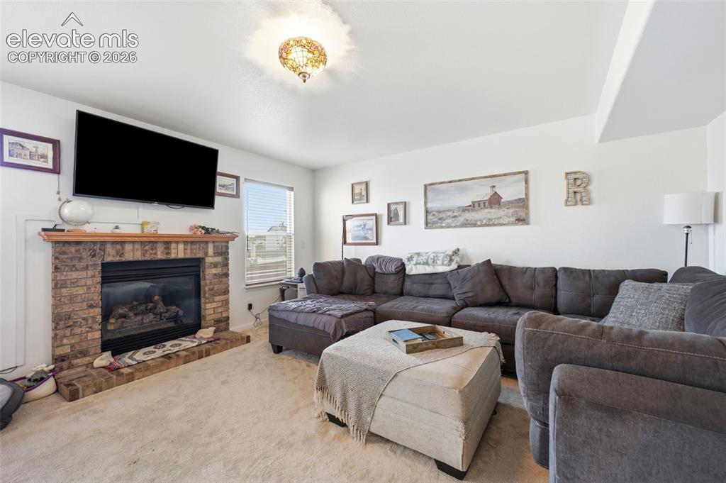 Image 12 of 40: Living area featuring a brick-surround fireplace with a wood mantel, a larg