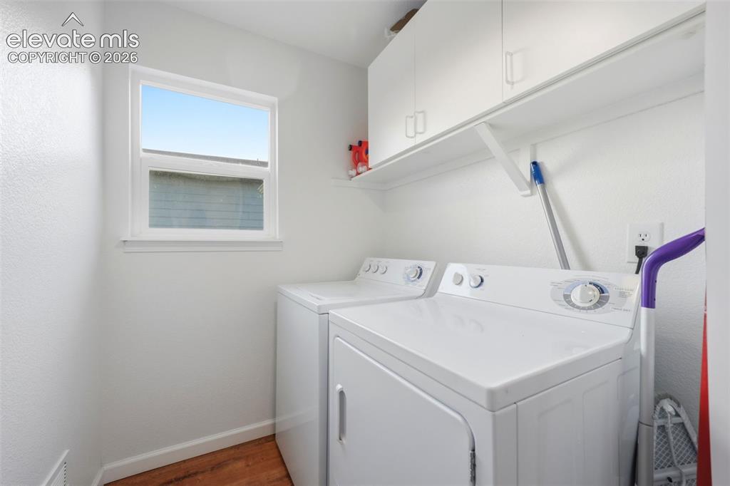 Image 15 of 40: Dedicated laundry space featuring a window, wood-finish flooring, and white