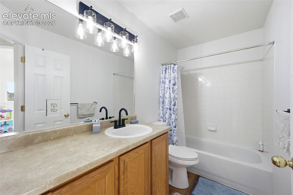 Image 16 of 40: Bathroom featuring a single vanity with wood-finish cabinetry, a large mirr