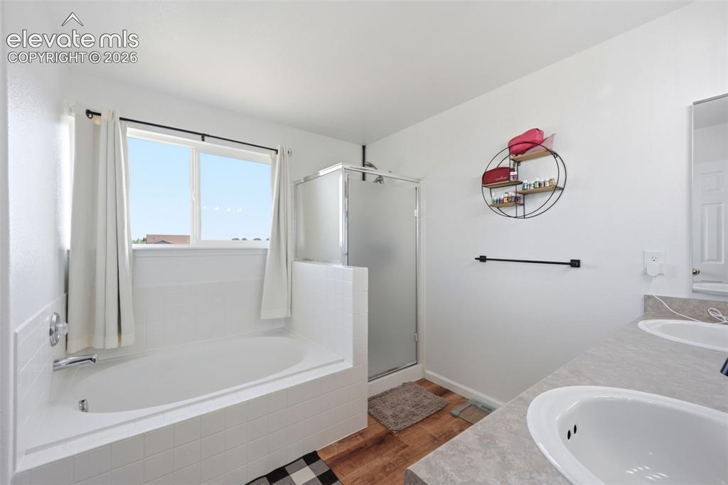 Image 20 of 40: White tiled tub surround with a built-in soaking tub, separate shower enclo