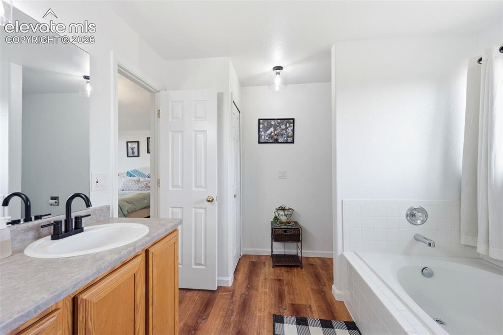 Image 21 of 40: Bathroom featuring a wood-finish floor, a single vanity with a laminate cou