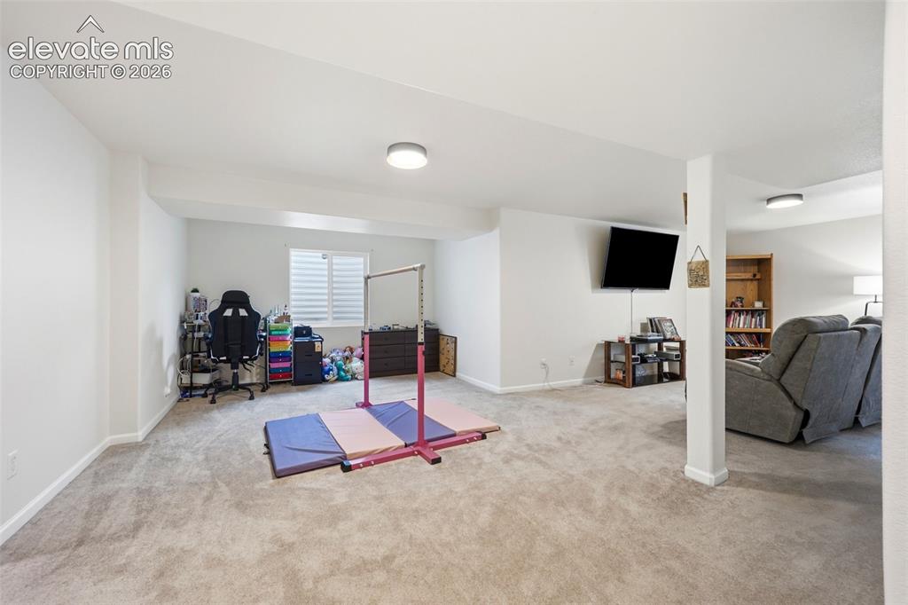 Image 22 of 40: Expansive carpeted room with recessed lighting and a window with horizontal