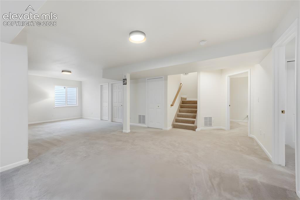 Image 24 of 40: Spacious room featuring light-toned carpeting, white walls, multiple doorwa