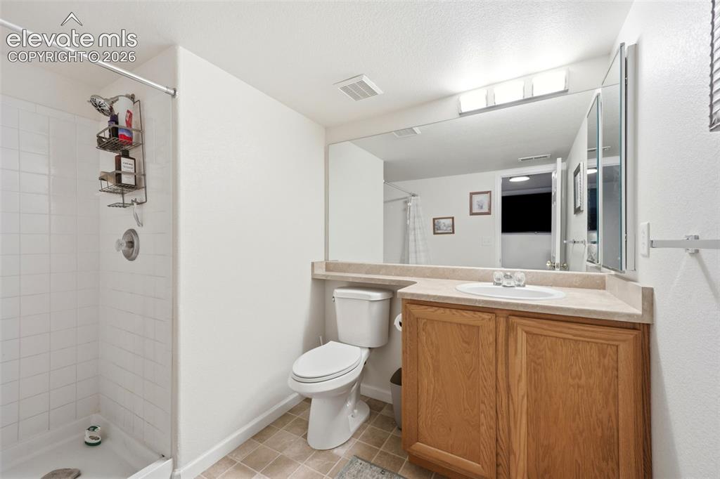 Image 26 of 40: Shower with white subway tile surround, wood-finish vanity with an integrat