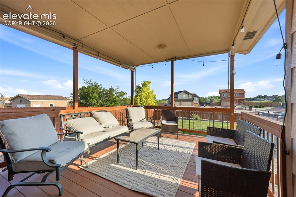 Image 27 of 40: Covered outdoor deck with wood-finish flooring, featuring a wooden railing 