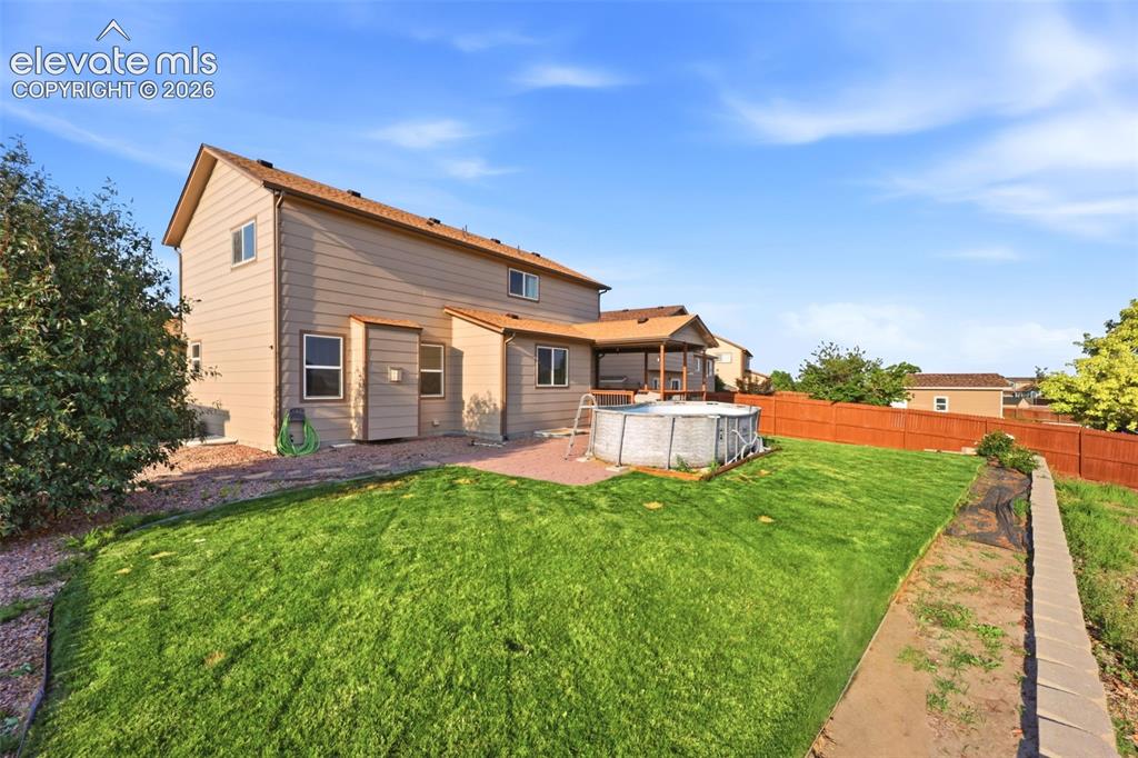 Image 31 of 40: Expansive backyard featuring a manicured lawn, wood fencing, and a concrete