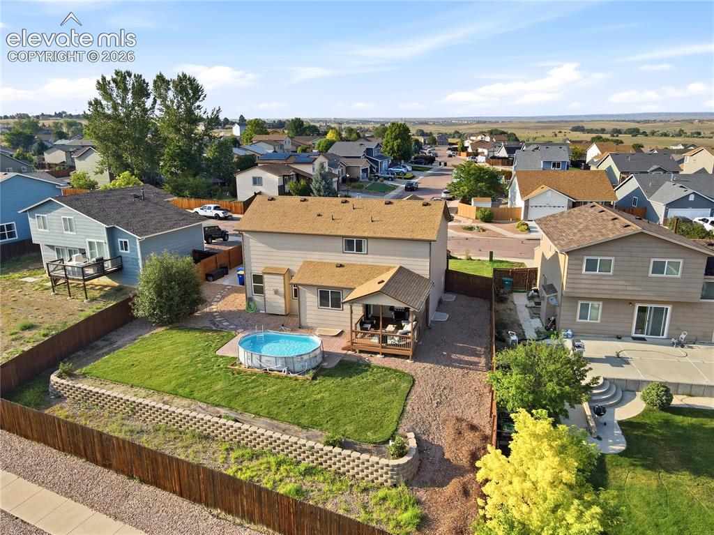 Image 36 of 40: Expansive backyard featuring a manicured lawn, retaining wall, and a covere