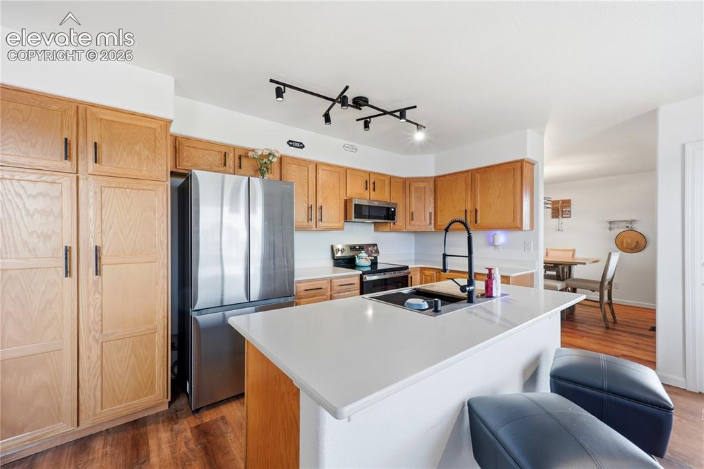 Image 8 of 40: Kitchen featuring wood-finish flooring, light wood cabinetry, stainless ste