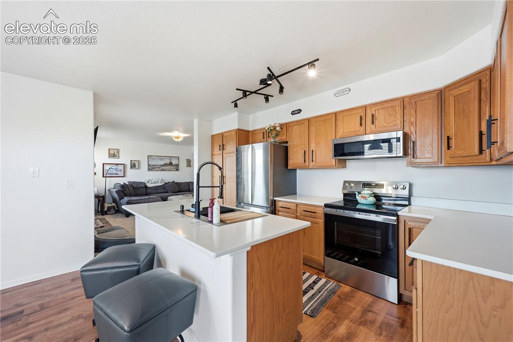 Image 9 of 40: Kitchen featuring wood-finish flooring, light wood cabinetry, stainless ste