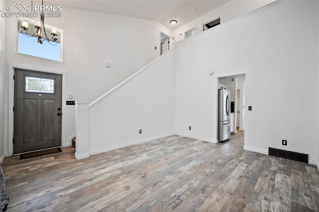 Image 10 of 50: Foyer entrance with high vaulted ceiling, wood finished floors, a chandelie