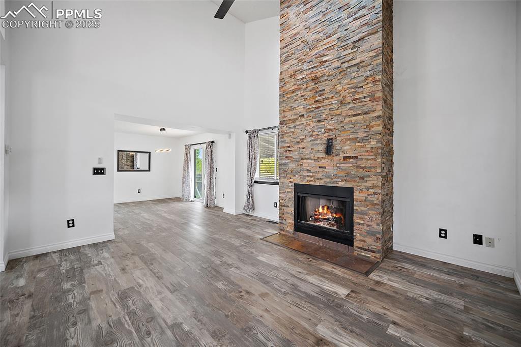 Image 14 of 50: Unfurnished living room featuring a high ceiling, a fireplace, wood finishe