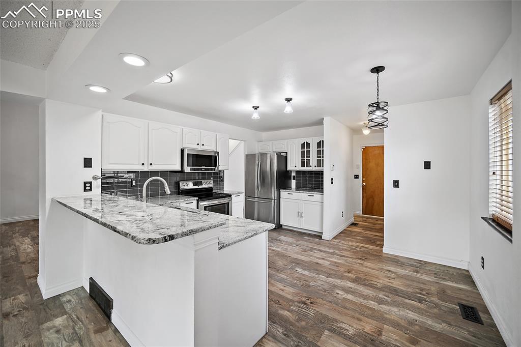 Image 18 of 50: Kitchen featuring decorative backsplash, white cabinetry, appliances with s
