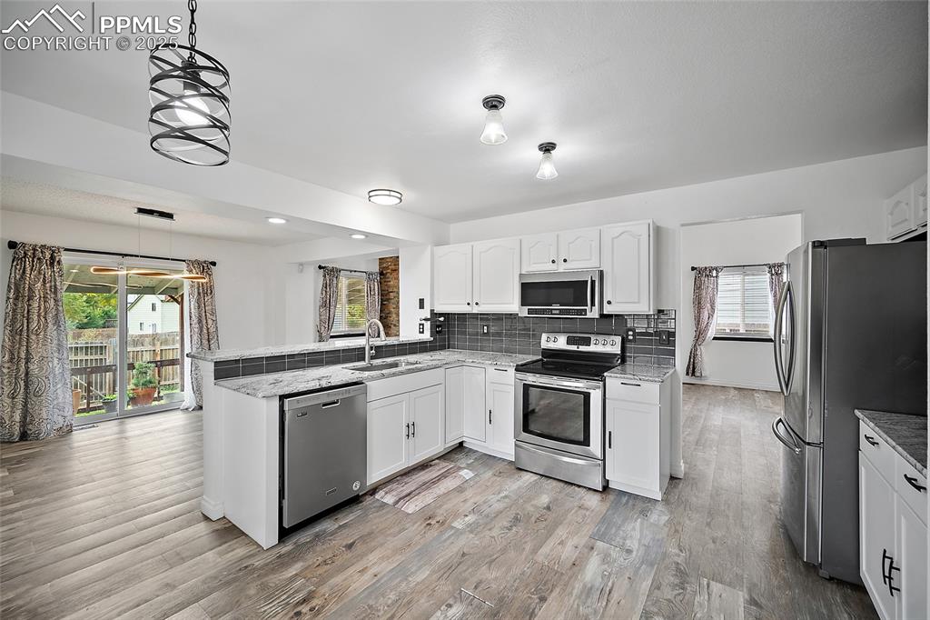 Image 19 of 50: Kitchen with tasteful backsplash, appliances with stainless steel finishes,