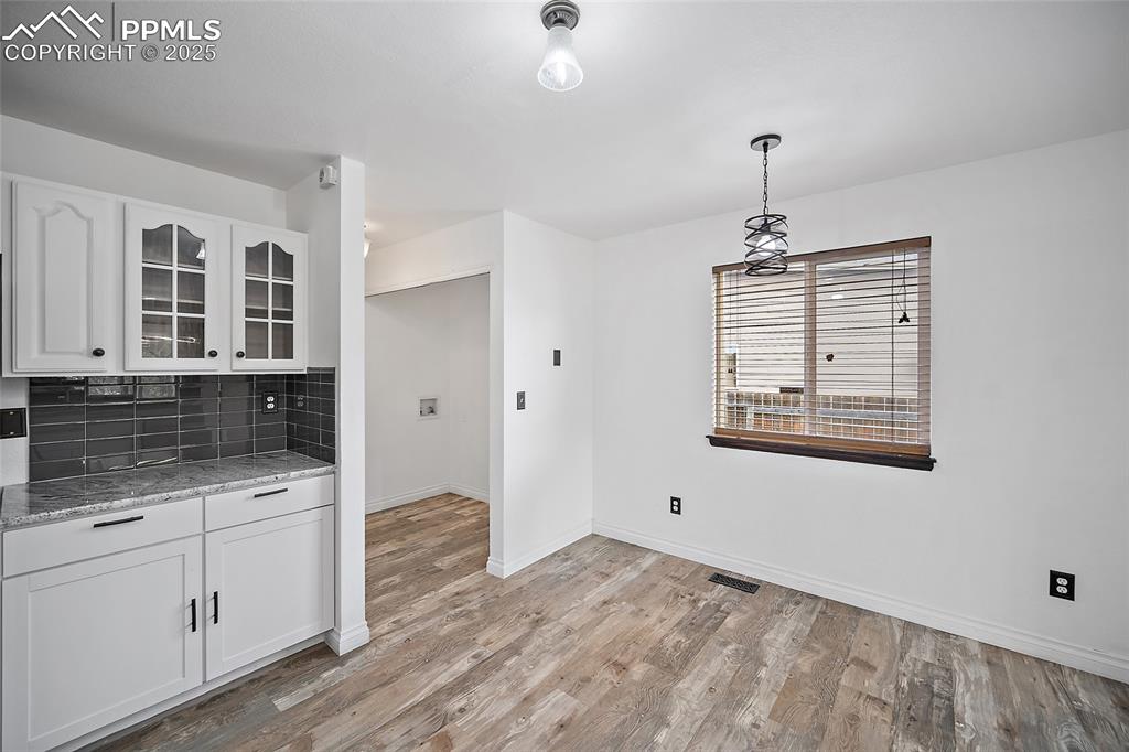 Image 20 of 50: Kitchen featuring light stone counters, tasteful backsplash, glass insert c