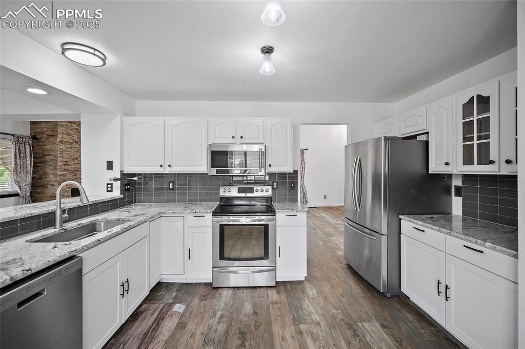 Image 21 of 50: Kitchen with light stone countertops, appliances with stainless steel finis