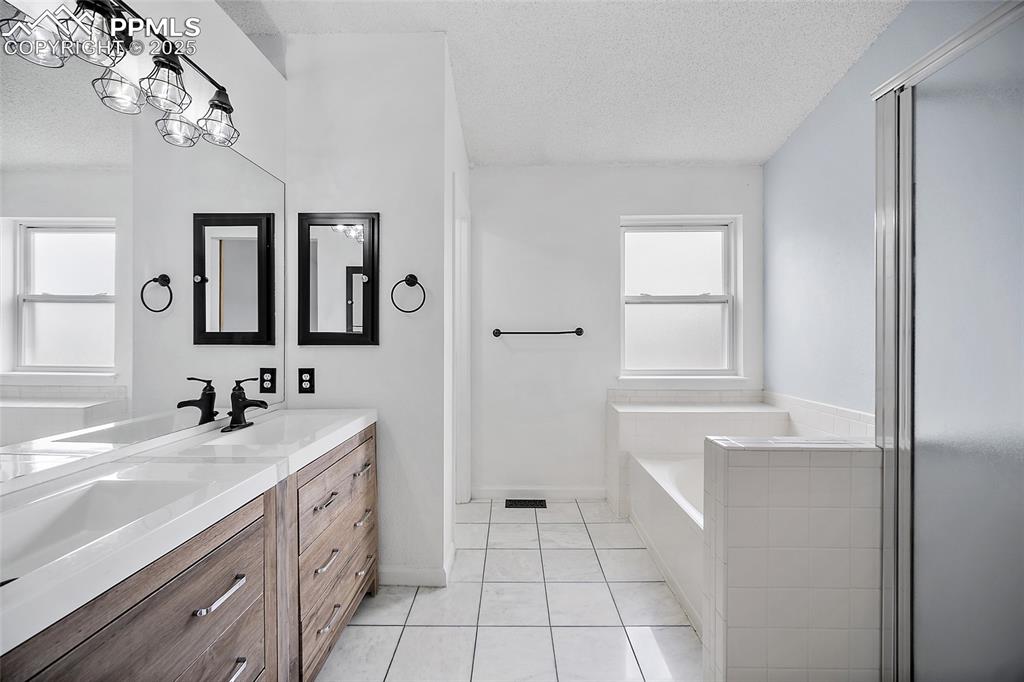 Image 31 of 50: Full bathroom with a textured ceiling, double vanity, light tile patterned 
