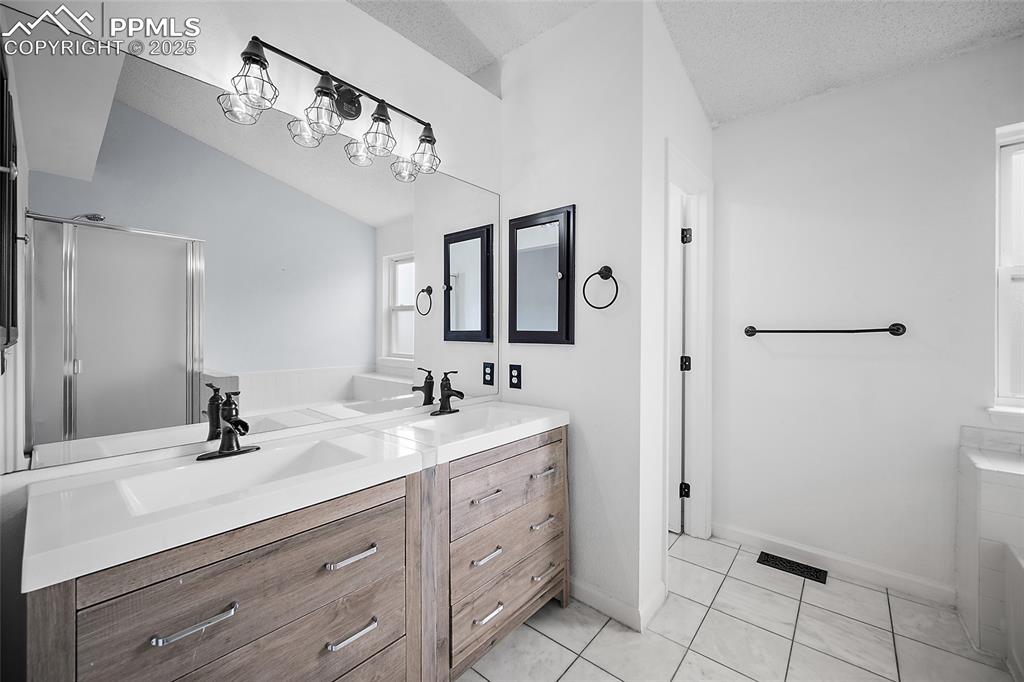Image 32 of 50: Bathroom featuring double vanity, light tile patterned floors, vaulted ceil
