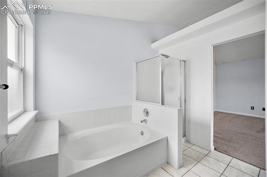 Image 33 of 50: Bathroom with a bath, light tile patterned floors, a shower stall, and ligh