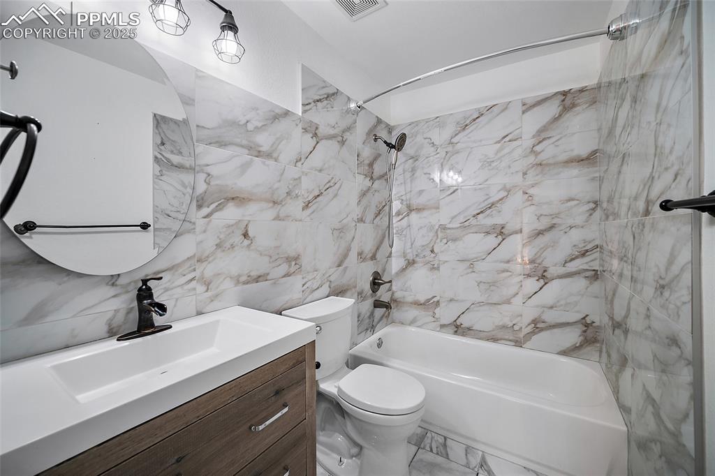 Image 36 of 50: Full bathroom with bathing tub / shower combination, vanity, tile walls, an