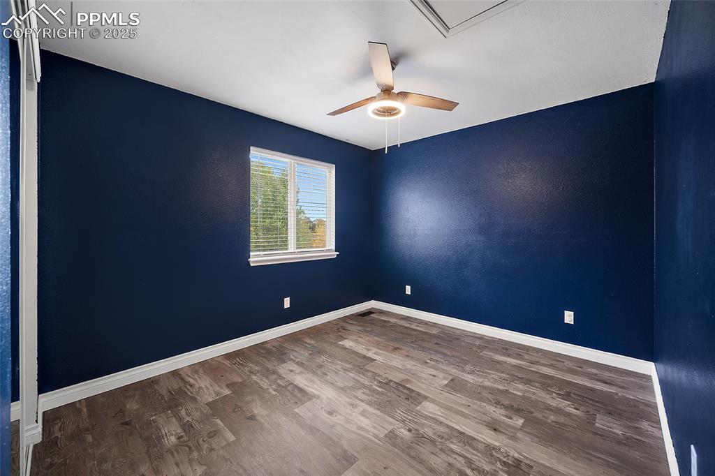 Image 37 of 50: Spare room featuring wood finished floors, ceiling fan, and attic access