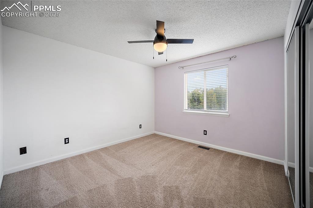 Image 39 of 50: Unfurnished bedroom featuring a textured ceiling, ceiling fan, and carpet